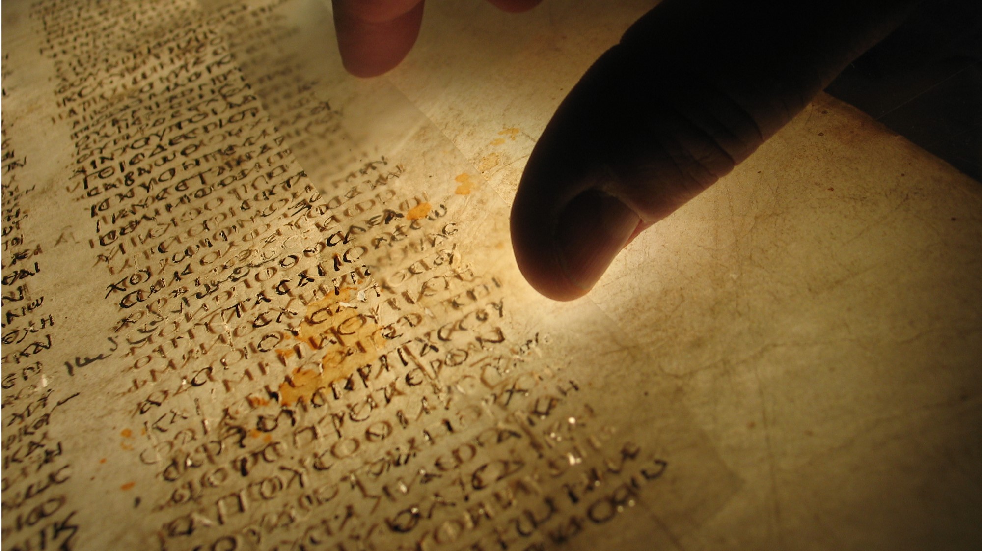 A backlit document made of yellow parchment with black script. 